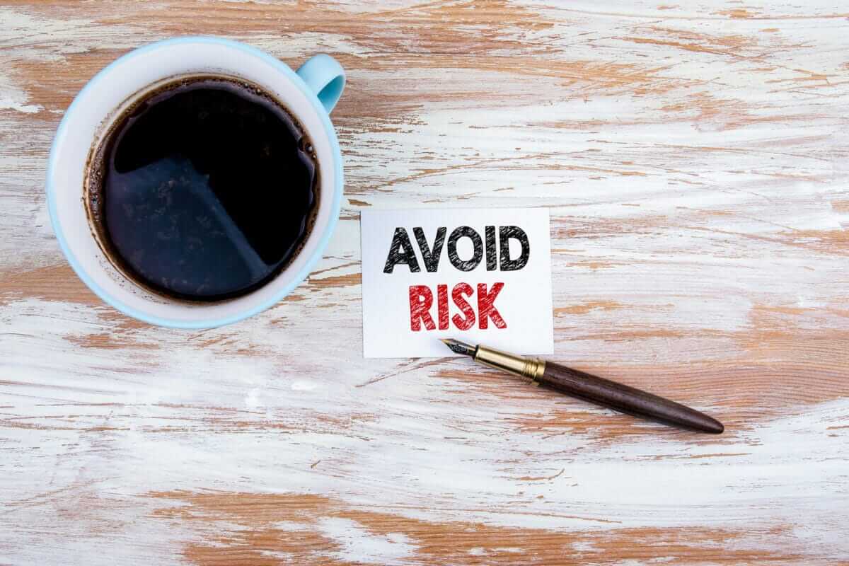 Avoid Risk concept. Paper letter and pen on a wooden table