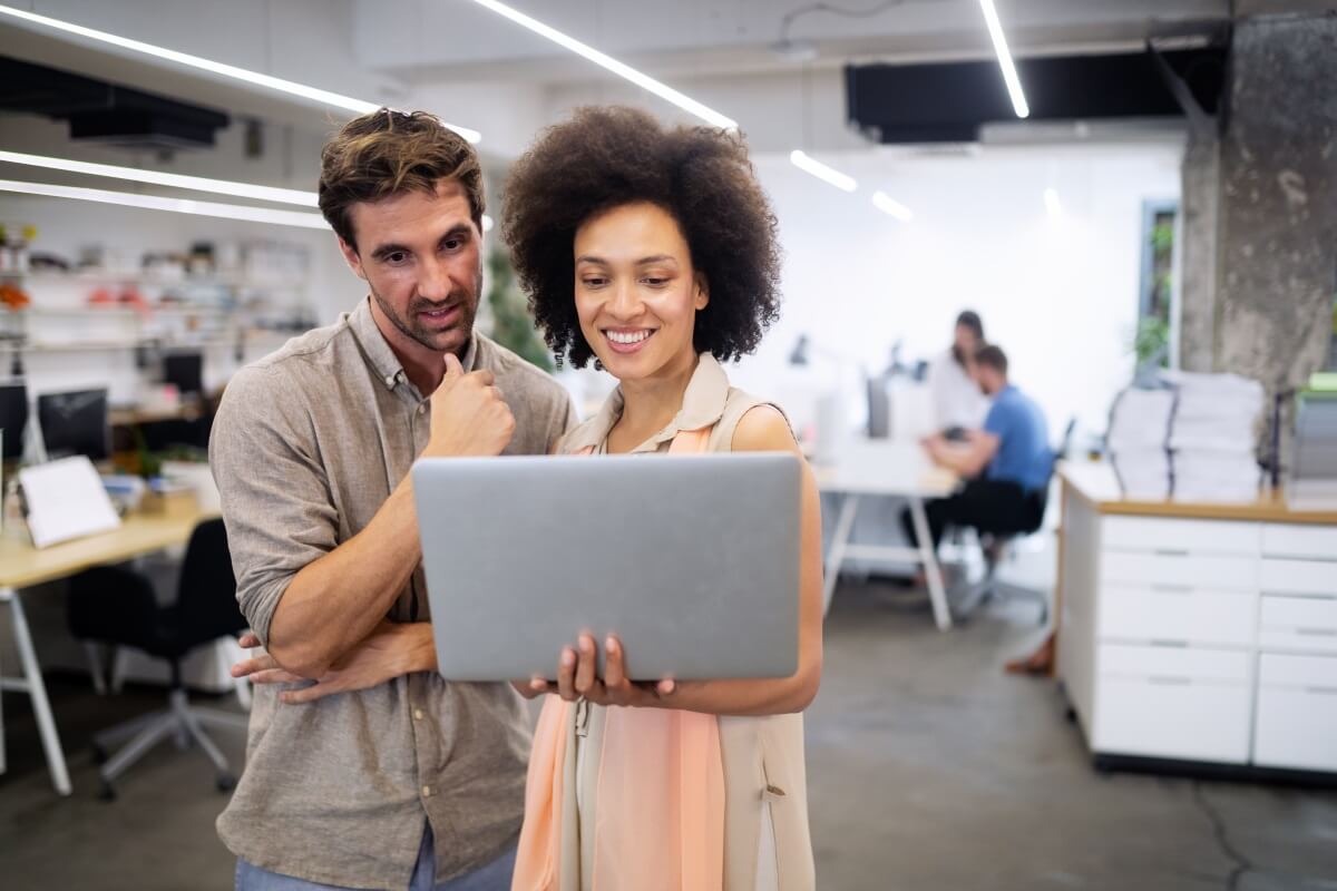 Two office workers looking at a laptop together